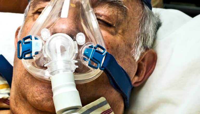 A older man sleeps wearing a CPAP mask