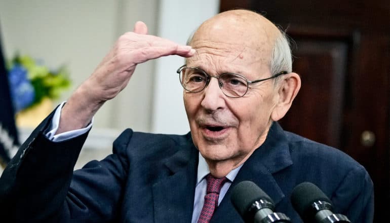 Stephen Breyer puts his hand to his forehead as he's speaking at a podium