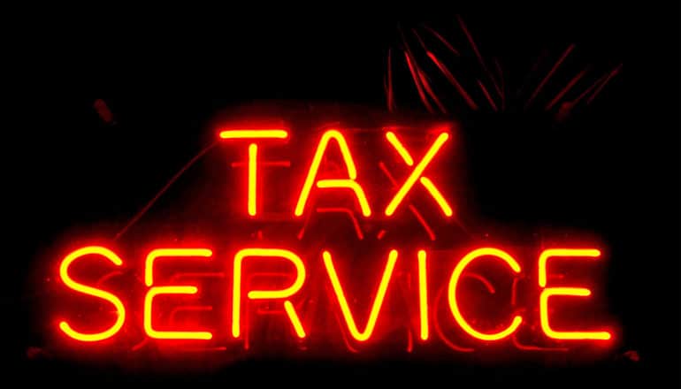 A neon sign reads "Tax Service"