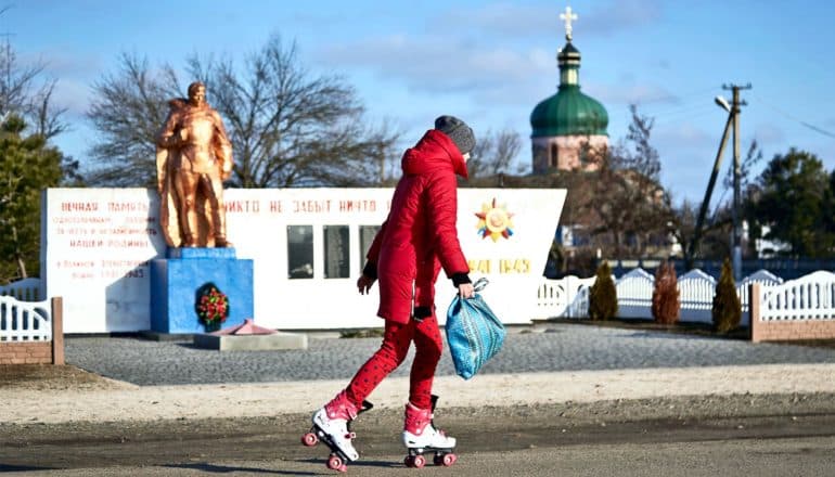 A young girl roller skates along a road