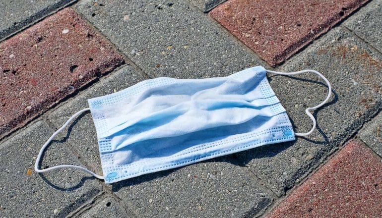 A medical mask laying on a city sidewalk made of bricks