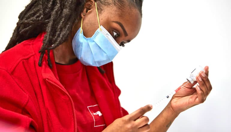 A health care worker fills a syringe with the covid-19 vaccine