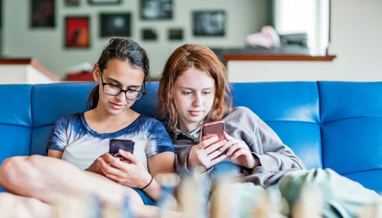 two teens on couch with phones