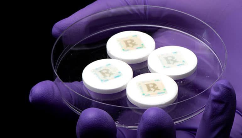 White pills in a petri dish have "stamps" on them that read "Rx"