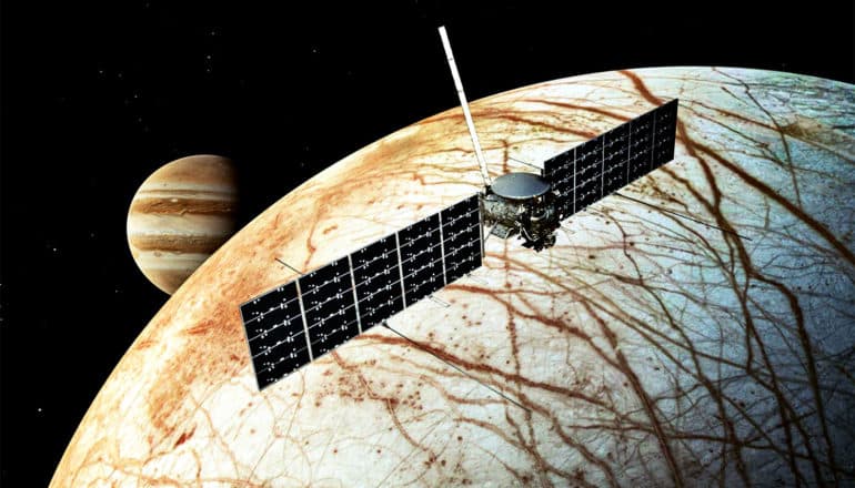 A satellite floats over Europa with Jupiter in the background