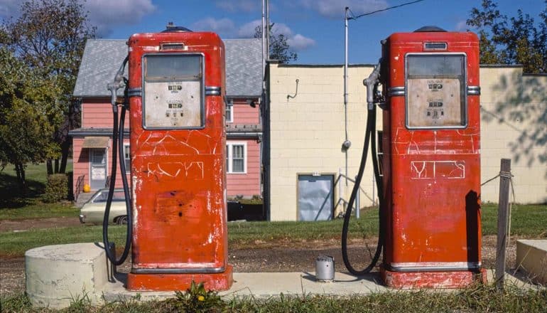 two old red gas pumps in front of house