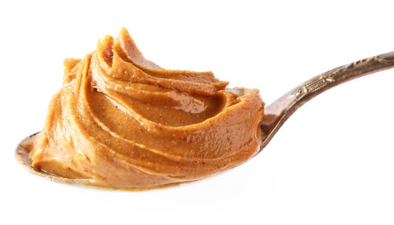 A spoonful of peanut butter against a white background