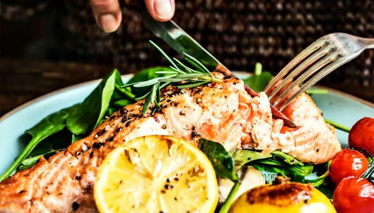 A person eats fish with a knife and fork