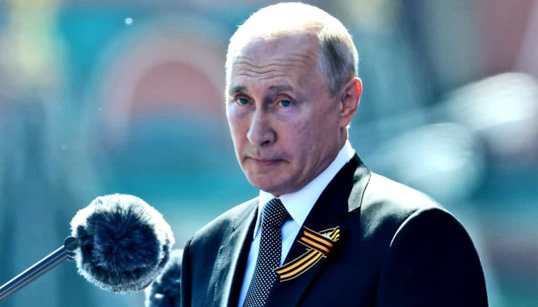 Vladimir Putin speaks in front of a microphone while outside