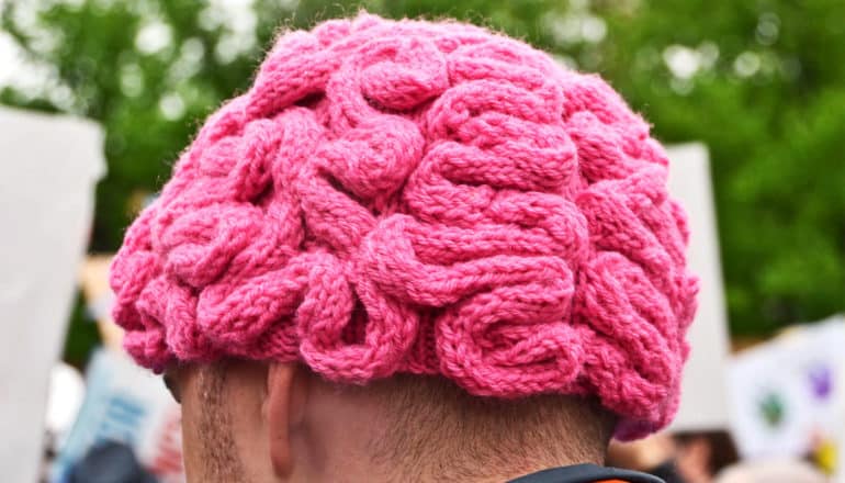 A man wears a pink knit cap that looks like a brain