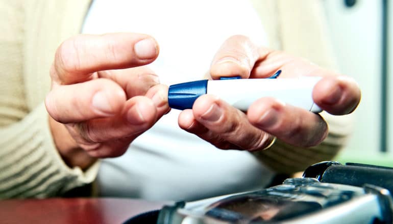 A woman checks her blood sugar with a diabetes finger stick tool