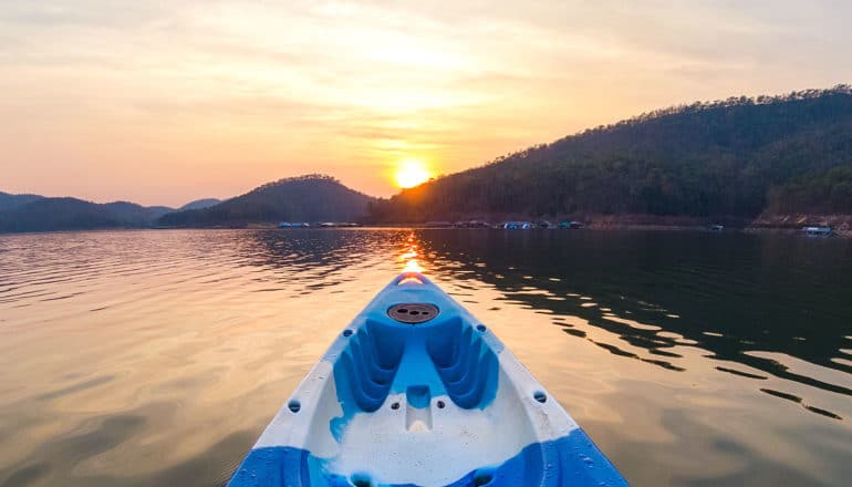 A kayak floats on a lake at sunset