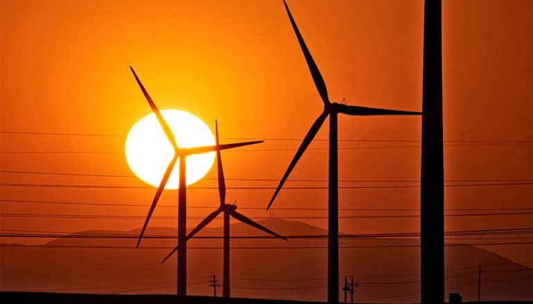 Wind power turbines spin at sunset