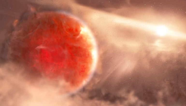 The reddish orange planet Aurigae b sits in a swirling gas and dust cloud with a star in the background