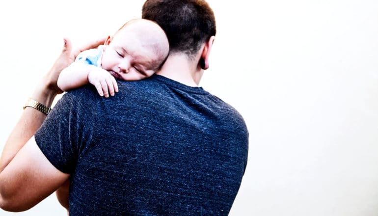 A father holds his sleeping newborn baby