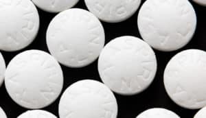 White aspirin pills sit on a black background.