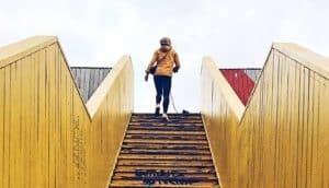 A woman walks up steep stairs while walking her dog.