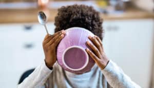 child drinks from cereal bowl