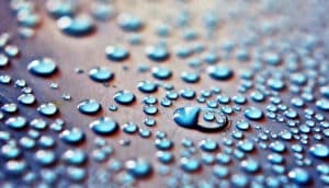 Beads of water on a surface with light shining on it.