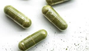 Several capsules filled with green tea extract on a white background.