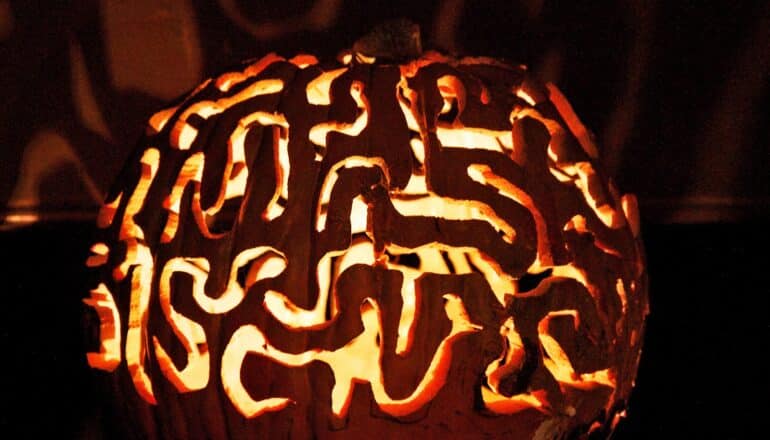 A pumpkin carved to look like a brain has a candle inside.