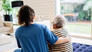 caregivers sits on bench with elderly Black woman