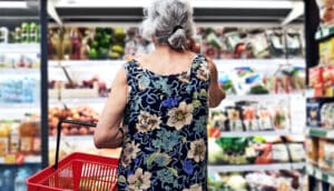 An older woman at the grocery looking at full shelves.