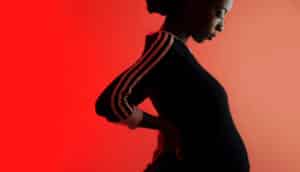 Black pregnant person in silhouette against red background