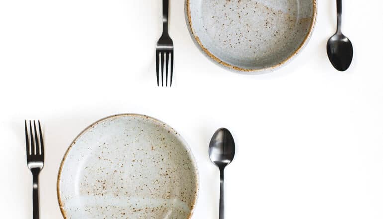 Two plates and two sets of silverware on a white background.