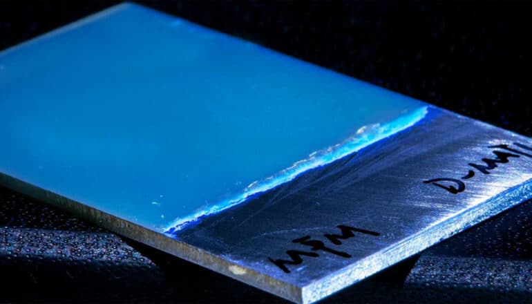 A blue material covering part of a rectangular piece of metal.