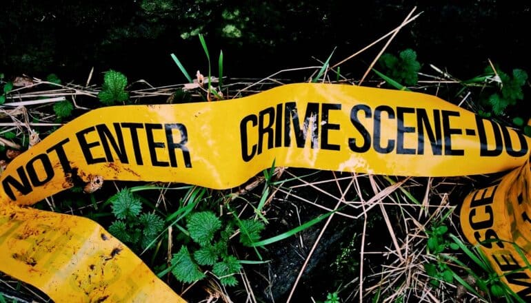 Yellow crime scene tape fallen on grass in the dark.