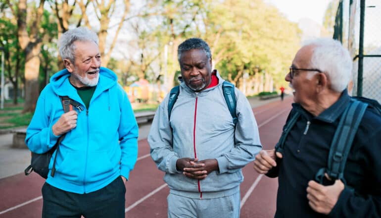 three older adults in athletic clothes outdoors