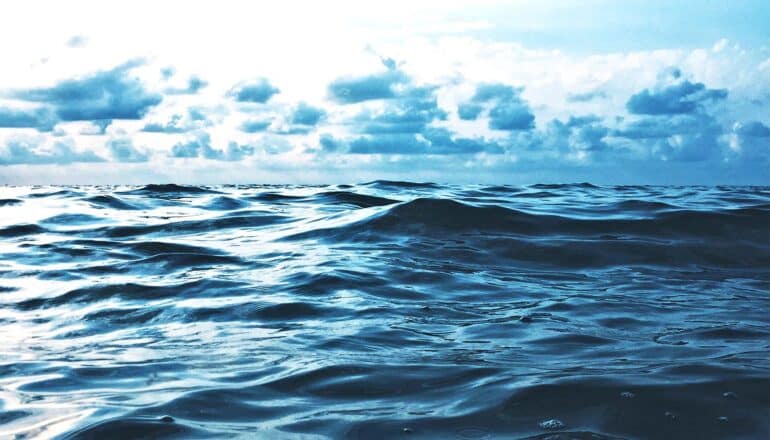 A shot of the surface of the ocean with clouds above.