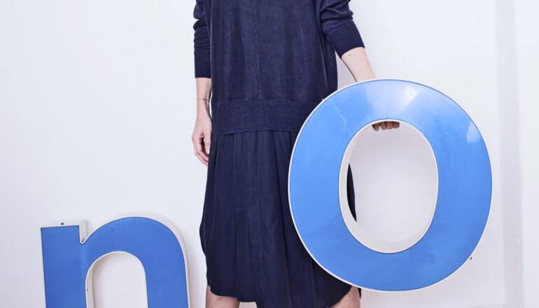 female figure holds up big blue "O" with "N" on floor behind her