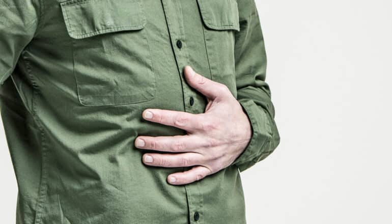 person in green shirt holds hand over stomach