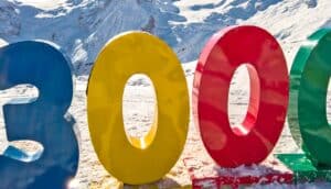 The number 3,000 in colorful plastic numbers sits on a snowy mountain range.