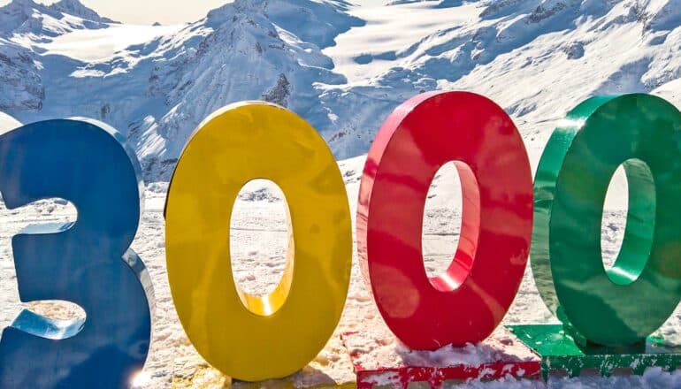 The number 3,000 in colorful plastic numbers sits on a snowy mountain range.