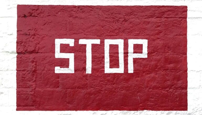 A red sign painted on a wall reads "Stop" in white letters.