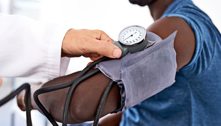 A doctor checks a young man's blood pressure with a cuff.