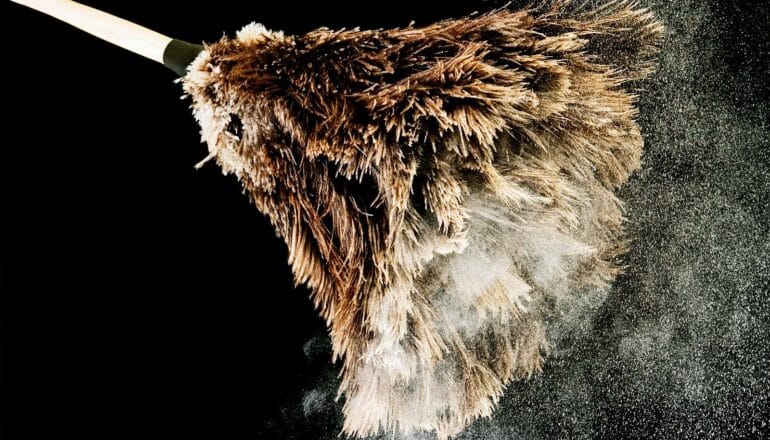 A feather duster has white dust coming off of it.