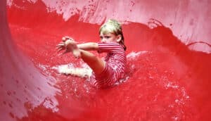 A young girl slides down a red waterslide.