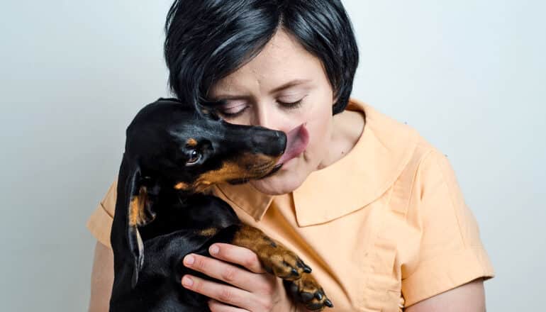 person holds dachshund up to her face