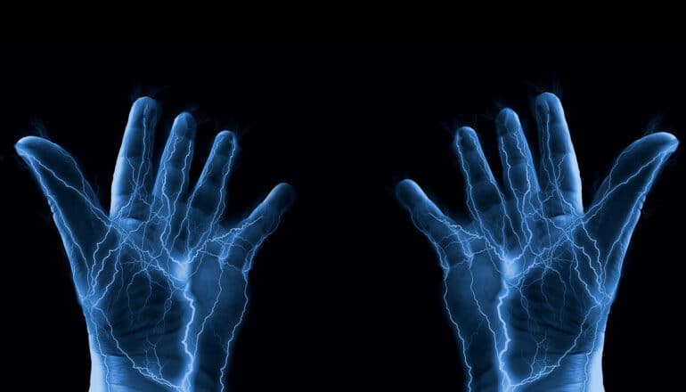 A person's hands with blue lightning-like electricity flowing through them.