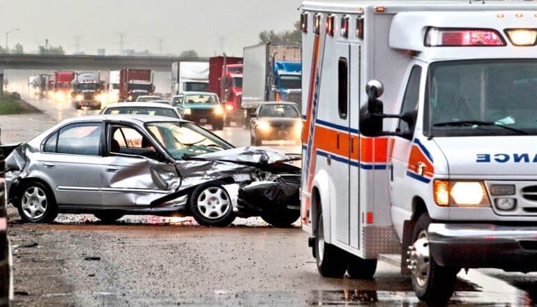 An ambulance at the scene of a car accident on a highway.