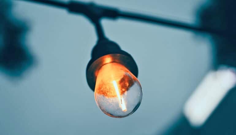 A single hanging light bulb on a string of outdoor lights.