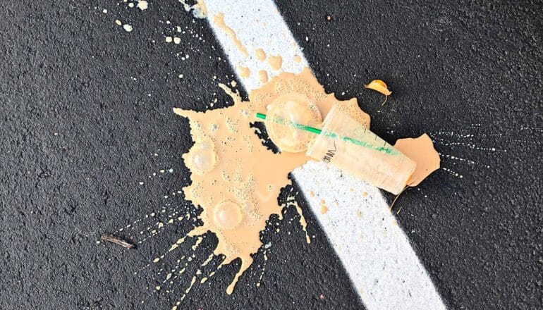 ice coffee spilled on pavement with white stripe