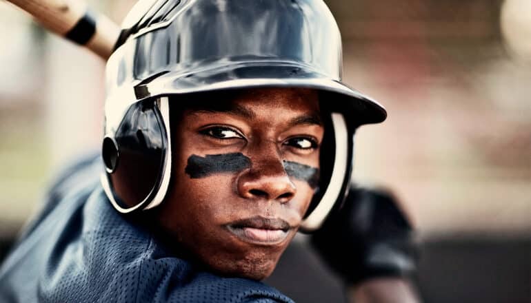 A baseball player waits for a pitch while holding a bat.