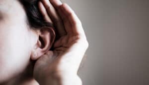 A woman cups her ear to hear better.