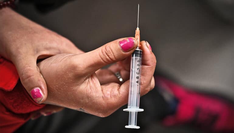 A person holds a syringe before injecting drugs.