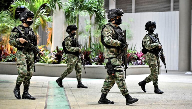 four armed military police officers walk in public square